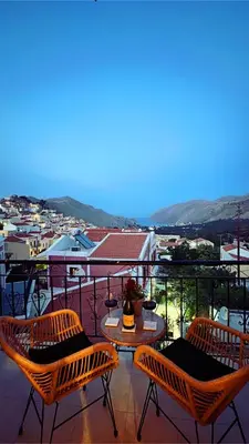 a balcony with three chairs and a table with a view at Casa Chara in Symi