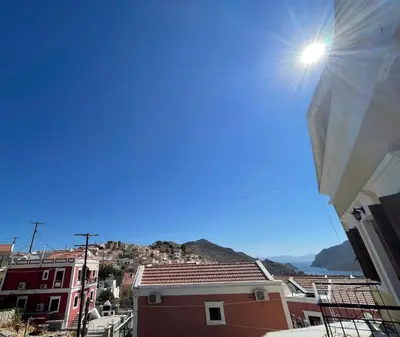 a view of a city with the sun in the sky at Casa Chara in Symi
