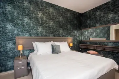a bedroom with a large bed with green wallpaper at Oleana City Center in Rhodes Town