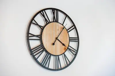 a black and wooden clock on a white wall at George's Paradise in Afantou