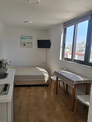 a bedroom with a bed and a table and a window at Small apartment (studio) in town with sea view in Rhodes Town
