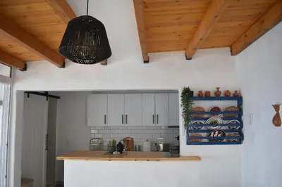 a kitchen with white walls and wooden ceilings at Stegna Rita's apartment in Archangelos
