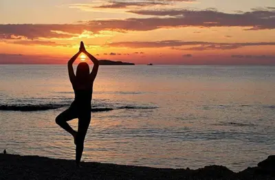 a woman doing yoga on the beach at sunset at Stegna Rita's apartment in Archangelos