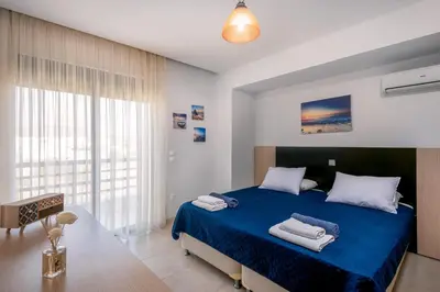 a bedroom with a blue bed and a large window at Blue Wave Villa - road view in Gennadi