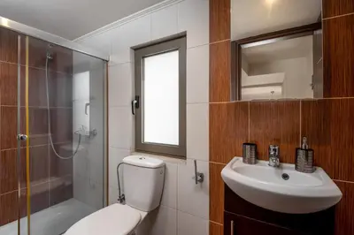 a bathroom with a toilet and a sink and a shower at Blue Wave Villa - road view in Gennadi