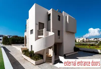 a white house with a spiral staircase on the side of it at Blue Wave Villa - road view in Gennadi