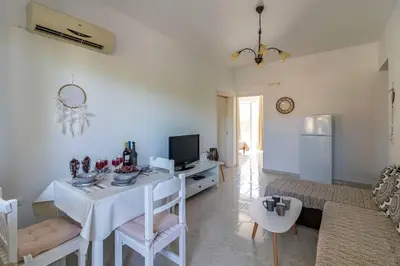 a white living room with a table and a couch at Fotis house in Afantou