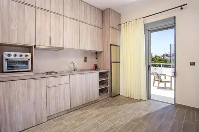 a kitchen with wooden cabinets and a sliding glass door at Oleana di Castello in Rhodes Town