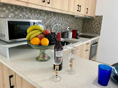 a bowl of fruit and a bottle of wine on a kitchen counter at Paraskevi's Apt - City Center w/ Lovely Park View in Rhodes Town