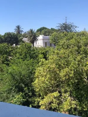 a white house on top of a hill with trees at Paraskevi's Apt - City Center w/ Lovely Park View in Rhodes Town