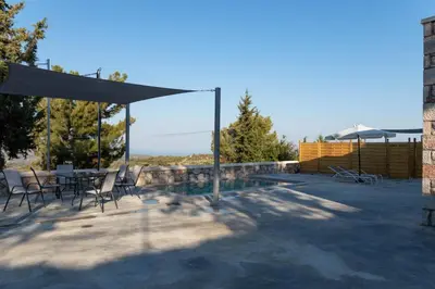a patio with a table and chairs and a pool at Villa Iliousa Grand in Psinthos
