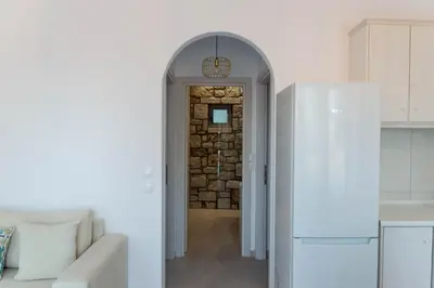 a kitchen with an archway and a white refrigerator at Villa Iliousa Grand in Psinthos