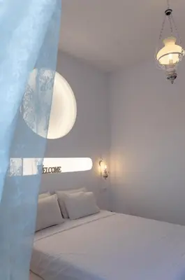 a white bedroom with a bed and a chandelier at Villa Iliousa Grand in Psinthos