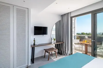 a bedroom with a bed and a desk with a tv at Kellys Luxury Apartments in Faliraki