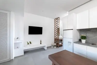 a kitchen with white cabinets and a tv on the wall at Kellys Luxury Apartments in Faliraki
