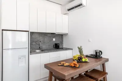 a white kitchen with a wooden table with fruit on it at Kellys Luxury Apartments in Faliraki