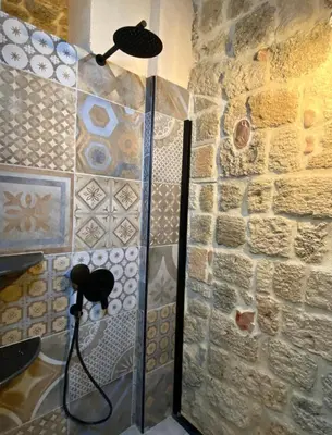 a shower in a room with a stone wall at Stone Cave Suite in Rhodes Town