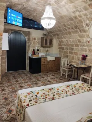 a bedroom with a bed and a table and a kitchen at Stone Cave Suite in Rhodes Town