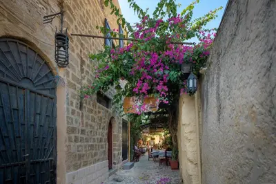 an alley with flowers hanging from the sides of buildings at Stone Cave Suite in Rhodes Town