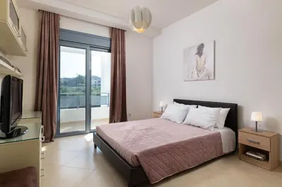 a bedroom with a bed and a tv and a balcony at Villa Rapha Maris in Afantou