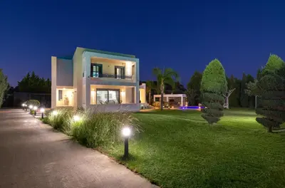 a large house with lights on the lawn at night at Villa Rapha Maris in Afantou