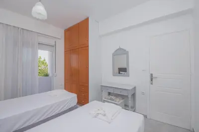 a white bedroom with two beds and a mirror at The Green Beauty in Pastida