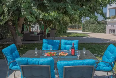 a table with blue chairs and a bottle of wine at The Green Beauty in Pastida
