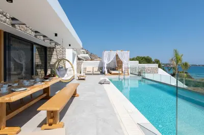 a house with a swimming pool with wooden benches at Villa Auretta in Pefki Rhodes