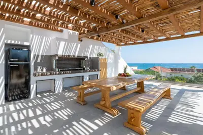 a wooden table and bench on a patio with a kitchen at Villa Auretta in Pefki Rhodes