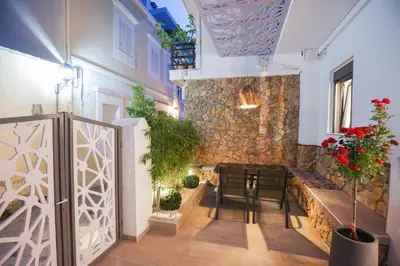 a room with a table and chairs and a stone wall at City Compass Luxury Suites in Rhodes Town