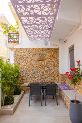a patio with two chairs and a table and a stone wall at City Compass Luxury Suites in Rhodes Town