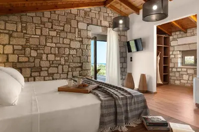 a living room with a stone wall and a bed at Villa Antheia in Kalathos