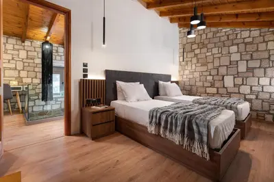 a bedroom with two beds and a brick wall at Villa Antheia in Kalathos