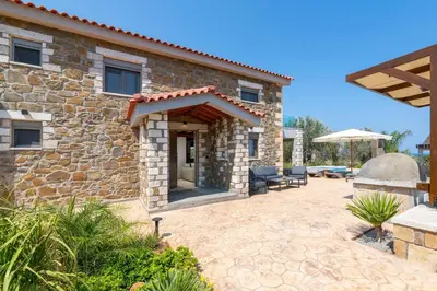 a stone house with a patio in front of it at Villa Antheia in Kalathos