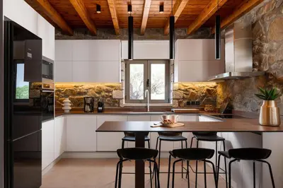 a kitchen with a wooden table and stools at Villa Antheia in Kalathos