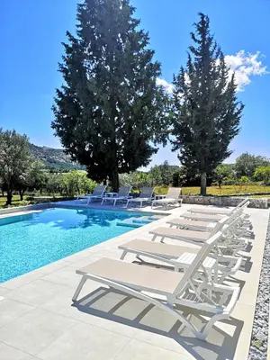 a row of lounge chairs next to a swimming pool at Chrysanthi Villa, Living in Nature in vlicha