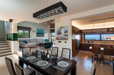 a dining room and living room with a table and chairs at Ethereum Villa in Asgourou