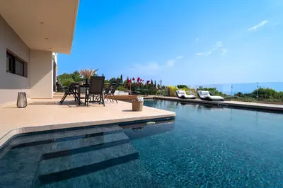 a swimming pool with two chairs and a house at Ethereum Villa in Asgourou