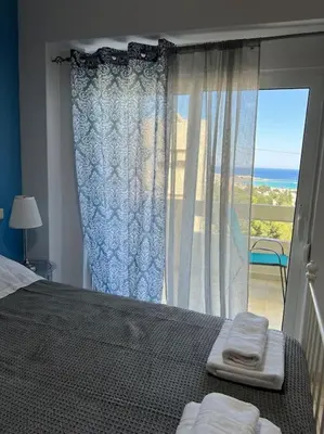 a bedroom with a bed and a large window at Karakonero view apartment in Rhodes Town