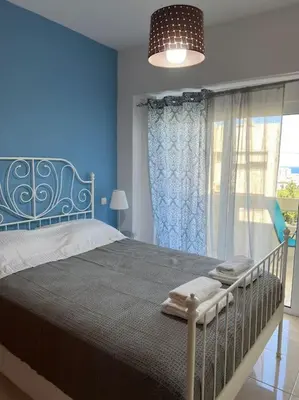 a blue bedroom with a bed and a window at Karakonero view apartment in Rhodes Town
