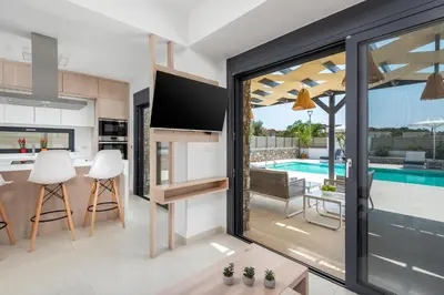 a kitchen and living room with a view of a swimming pool at Lindian Palms in Lardos