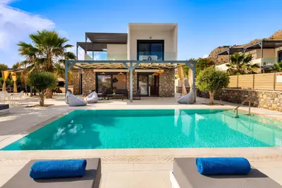 a swimming pool in front of a house at Lindian Palms in Lardos