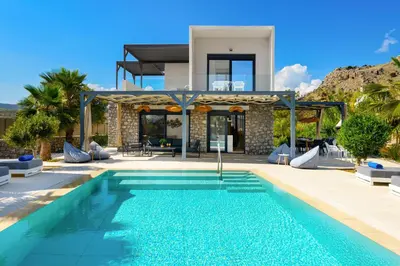 a villa with a swimming pool in front of a house at Lindian Palms in Lardos