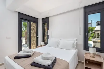 a white bedroom with a large bed with towels on it at Lindian Palms in Lardos