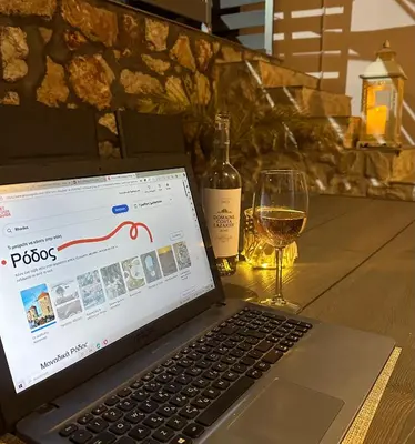 a laptop computer sitting on a table with a glass of wine at Villa Massari in Haraki