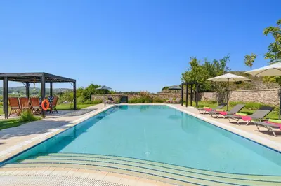 a swimming pool with chairs and umbrellas at Villa Amarandes With Private Pool in Paradeísion