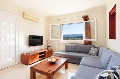 a living room with a blue couch and a tv at Villa Amarandes With Private Pool in Paradeísion