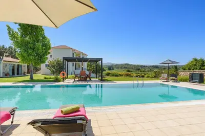 a swimming pool with chairs and an umbrella at Villa Amarandes With Private Pool in Paradeísion