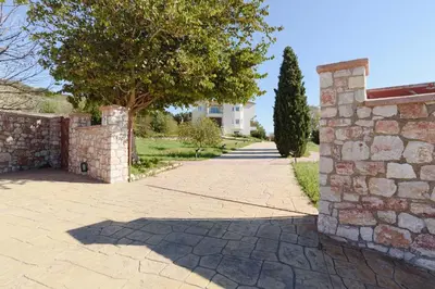 a stone wall and a driveway with a tree at Villa Amarandes With Private Pool in Paradeísion