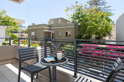 a table and two chairs on a balcony with pink flowers at Rhodes city studios in Rhodes Town